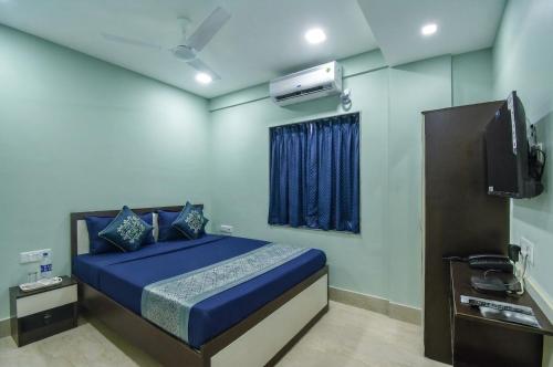 a bedroom with a blue bed and a television at FabHotels Calyra in Karīmnagar