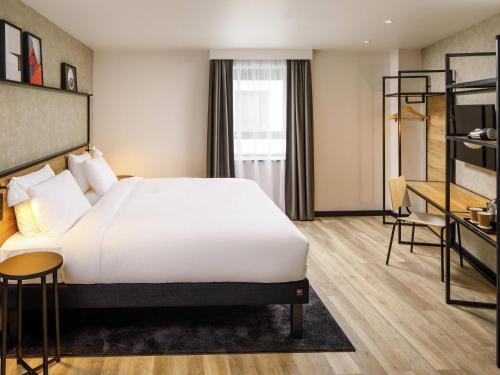 a hotel room with a large bed and a desk at Ibis Bourgoin Jallieu Medipole in Bourgoin