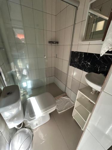 a white bathroom with a toilet and a sink at Suíte de Lane e Mú 2 in Abraão