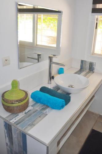eine Badezimmerablage mit Waschbecken und Spiegel in der Unterkunft Hôtel Mango GI in Saly Portudal