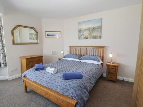 a bedroom with a bed with blue pillows and a mirror at Roma in Rhos-on-Sea