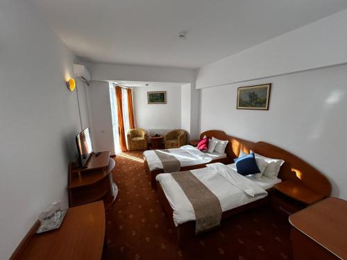 a hotel room with two beds and a television at Hotel Atlantis in Tulcea