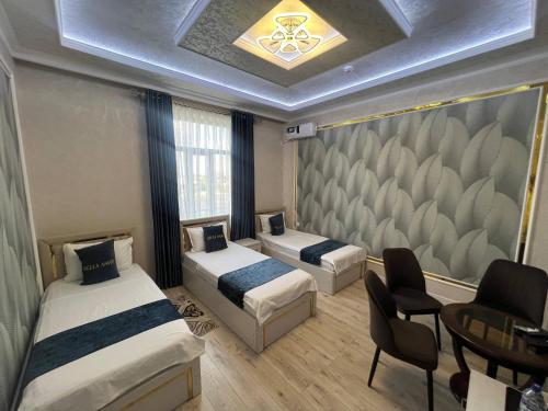 two beds in a room with a table and chairs at Bella Hotel Navoi in Karmana