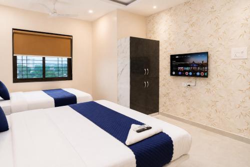 two beds in a hotel room with a tv at Hotel New Rajkamal in Aurangabad