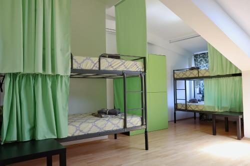two bunk beds in a room with green walls at Drenak Hostel in Skopje
