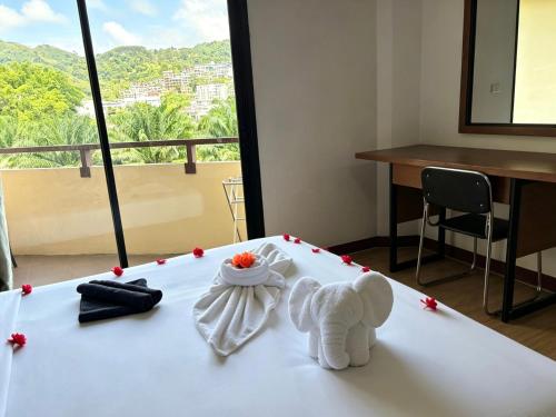 a white teddy bear sitting on top of a bed at patong v hotel in Patong Beach