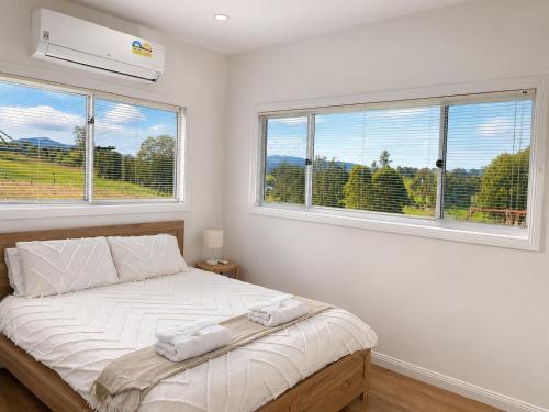 a bedroom with a large bed with two windows at Tangory Farmstay in Glendon Brook
