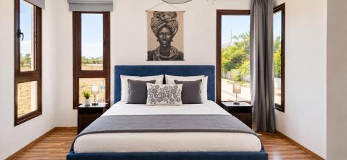 a bedroom with a blue bed with two windows at Palm Tree Villa By Staycom in Oroklini