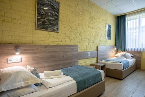 a bedroom with two beds and a yellow brick wall at Art хостел-готель "Адреналін" in Lutsk