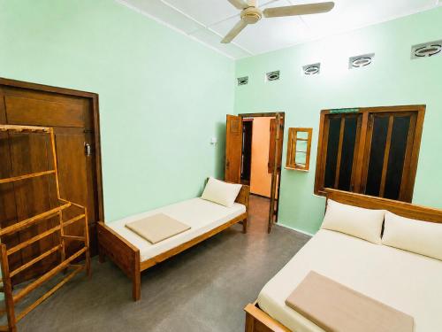 a bedroom with two beds and a ceiling fan at Yarl Retreat - Jaffna Town - Non-AC in Jaffna
