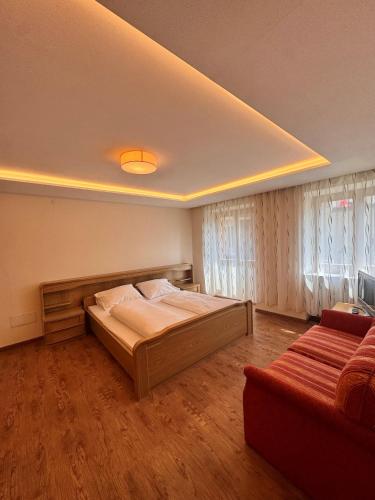 a bedroom with a bed and a couch at Hotel Goldenes Kreuz - since 1605 in Vipiteno