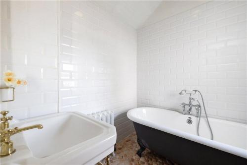 a white bathroom with a black and white tub at Biddy's Cottage Dalkey in Dublin