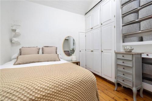 a white bedroom with a bed and a mirror at Biddy's Cottage Dalkey in Dublin