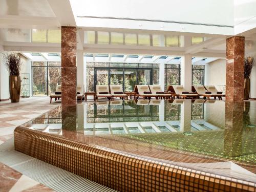 a large lobby with chairs and a pool at Mercure Palanga Vanagupe Resort & SPA in Palanga