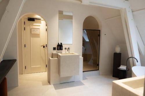 a white bathroom with a sink and a mirror at Priorij Corsendonk in Oud-Turnhout
