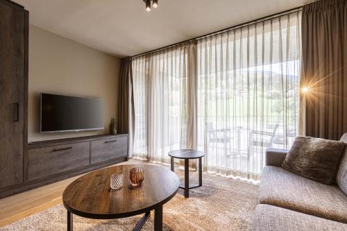 a living room with a tv and a couch and a table at Montafon Suites Schruns by ALPS RESORTS in Schruns