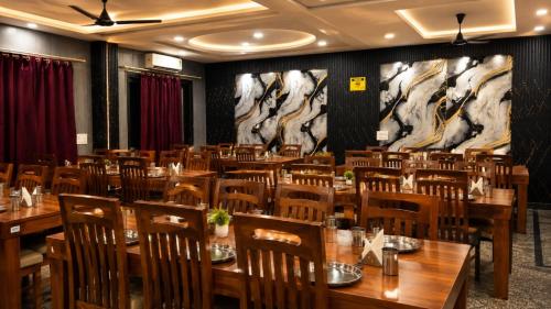 a restaurant with wooden tables and chairs and horses on the wall at Triveni Hotel And Restaurant in Barsāna