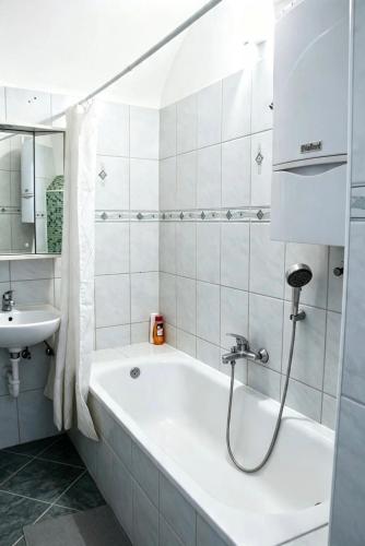 a white bathroom with a tub and a sink at Heritage Courtyard Apartment in Bruck an der Leitha