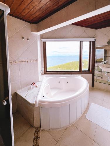 a large white tub in a bathroom with a window at Sentinelas do Mar in Arraial do Cabo