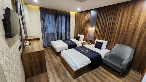 a hotel room with two beds and a chair at Al Baron Hotel - فندق البارون in Al Mawşil