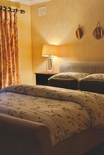 two beds in a room with a lamp and curtains at Kiltumper Lodge in Kilmihil