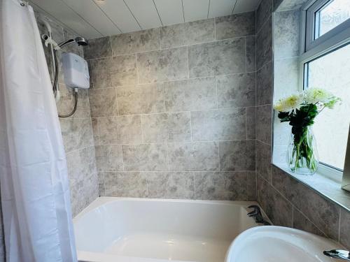 a bathroom with a tub and a vase of flowers at Bolton Terrace - 2 Bedrooms - Sleeps 4 in Workington