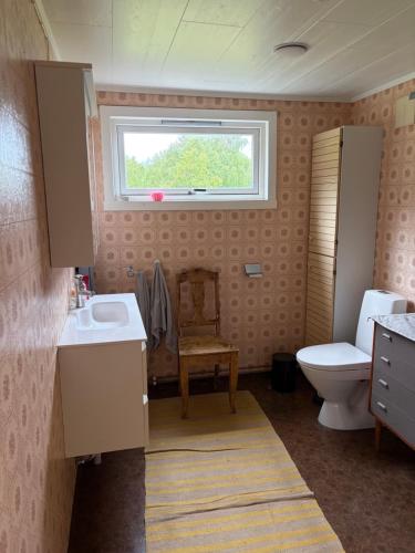 a bathroom with a toilet and a sink and a window at Cozy small house with amazing view in Hennes