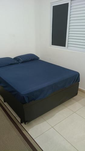 a bedroom with a bed with blue sheets and a window at Hostel Viracopos in Campinas