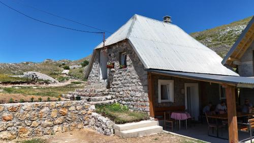 a small stone house with a roof on a hill at Miris Katuna - Sinjajevina in Šavnik