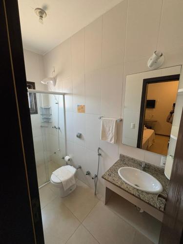a bathroom with a sink and a toilet and a mirror at Hotel Pousada Capão in Garopaba