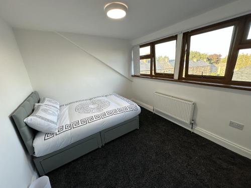 a small bedroom with a bed and two windows at PLUS PROPERTIES Leeds 6 in Bradford