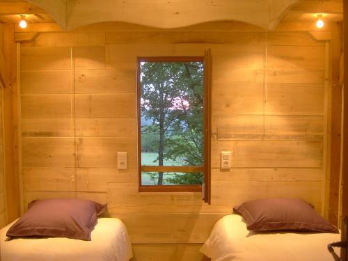 zwei Betten in einem Zimmer mit Fenster in der Unterkunft Les Cabanes du Tertre in Urval