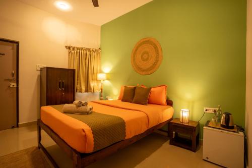 a bedroom with two beds with orange and green walls at Seraya Stays in Mandrem