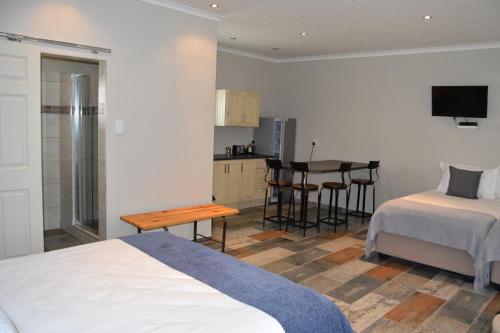 a bedroom with a bed and a kitchen with a table at Quiver Inn Guesthouse in Keetmanshoop