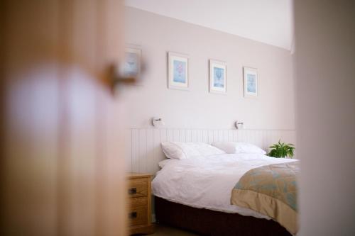 een slaapkamer met een wit bed en foto's aan de muur bij Scion Hill Gate Lodge in Hillsborough