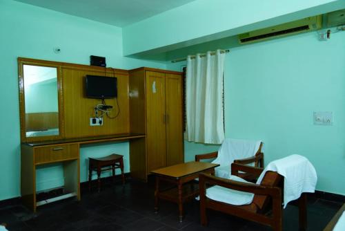 a room with a desk and a table and chairs at Balaji inn in Anantapur
