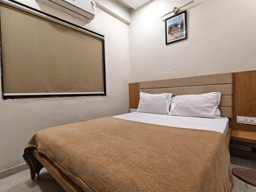 a bedroom with a bed and a large window at Hotel Sai Praatham in Shirdi