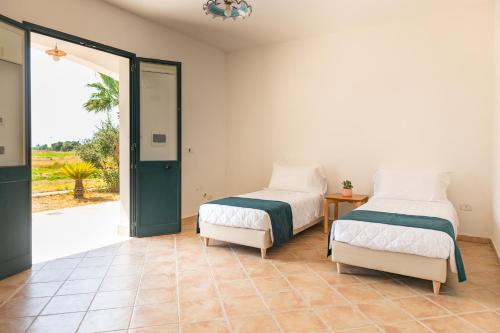 zwei Betten in einem Zimmer mit einer Tür, die auf eine Terrasse führt in der Unterkunft Baglio Basile - CDSHotels in Petrosino
