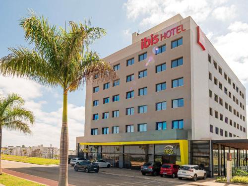 a hotel with a palm tree in front of it at ibis Lavras in Lavras