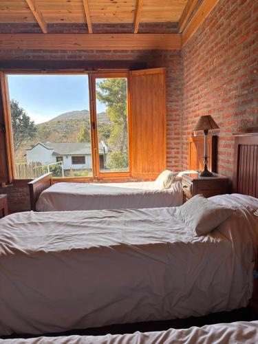 two beds in a room with a large window at Quinta Ecuador Tandil in Tandil