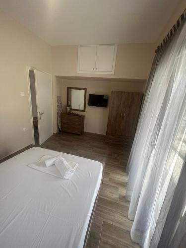 a bedroom with a white bed and a television at Paulos&Mary Apartment in Flogita
