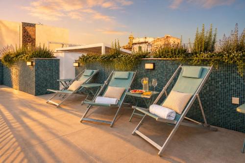 three chairs and a table on a patio at Posada de los Venerables in Seville