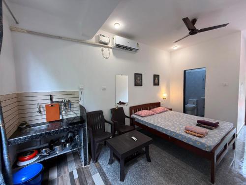 a room with a bed and a table and a sink at Studio Serinity Cove R-2 by Mukund Sadan Arambol in Arambol