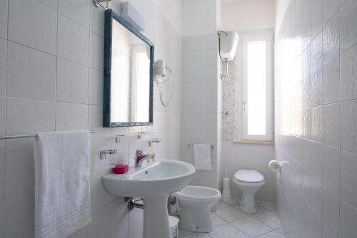 a white bathroom with a sink and a toilet at Camping Villaggio Calypso in Cupra Marittima
