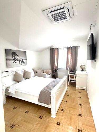 a white bedroom with a bed and a couch at Herz Apartmani in Igalo
