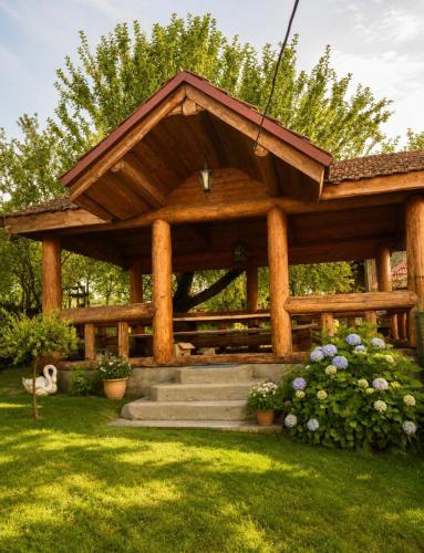 a wooden gazebo with stairs and flowers in a yard at Солочин Квітка Полонини Дом 63 in Solochyn