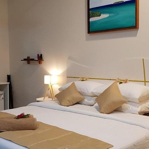 two beds in a bedroom with a picture on the wall at South Ari Inn in Mandhoo