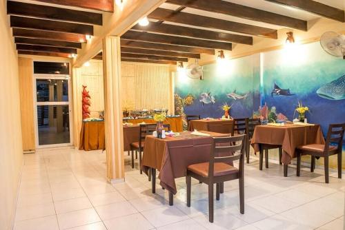 a dining room with tables and chairs and a fish mural at South Ari Inn in Mandhoo