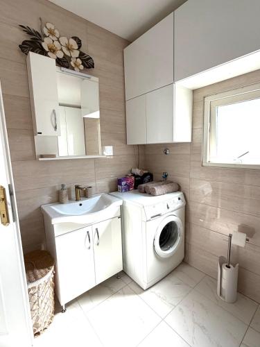 a bathroom with a washing machine and a sink at Herz Apartmani in Igalo