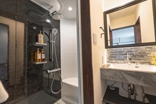 a bathroom with a shower and a sink and a mirror at Villa Arco Miyakojima in Miyako-jima